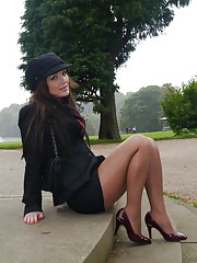 Girl in showing off her sexy legs in barely visible pantyhose and stiletto heels outdoors