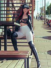 Exhibitionist Jeny Smith, wearing white tights, high leather boots and a black leather jacket, poses for a photoshoot on a crowded street.